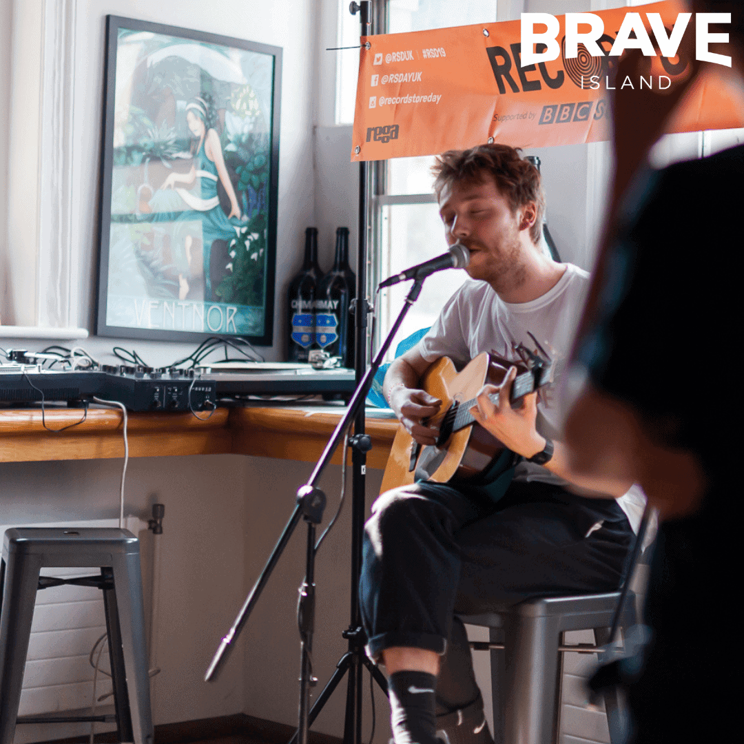 man plays guitar and sings in a record shop