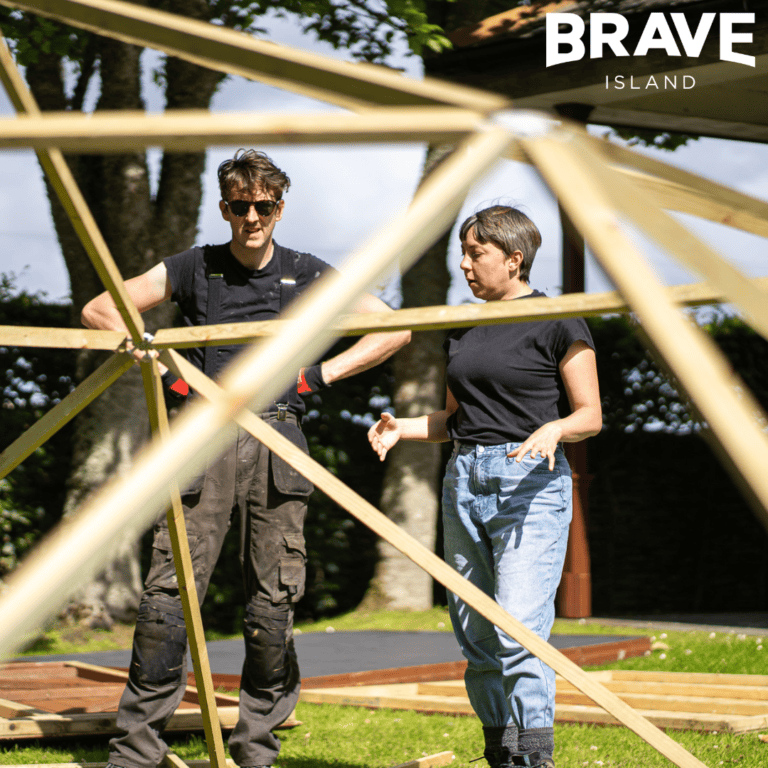 two people look at a wooden structure during the build of the people's palace of possibility