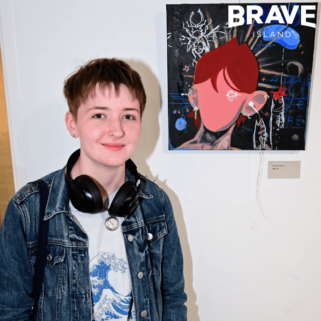 young creative of the month for may, lewis corry, smiling infront of their artwork