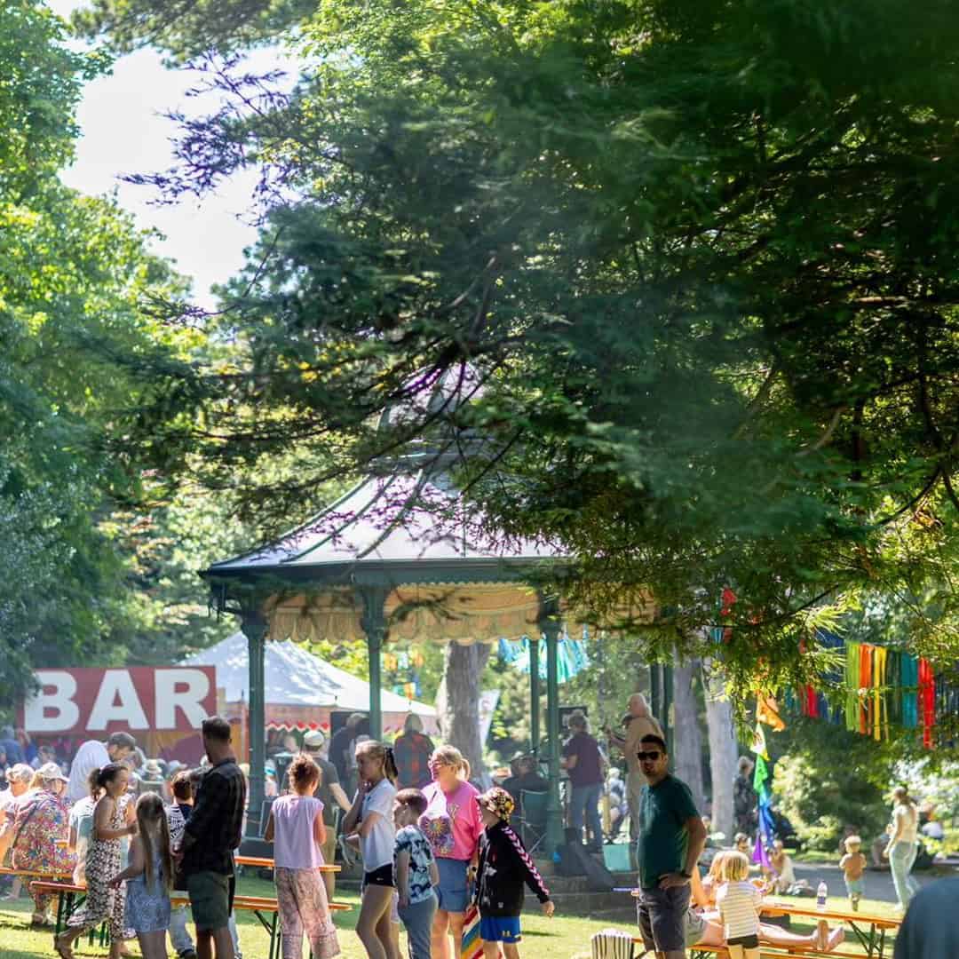 Photo of the Bandstand in Ventnor Park, with people around enjoying the Fringe Village as part of Ventnor Fringe Festival