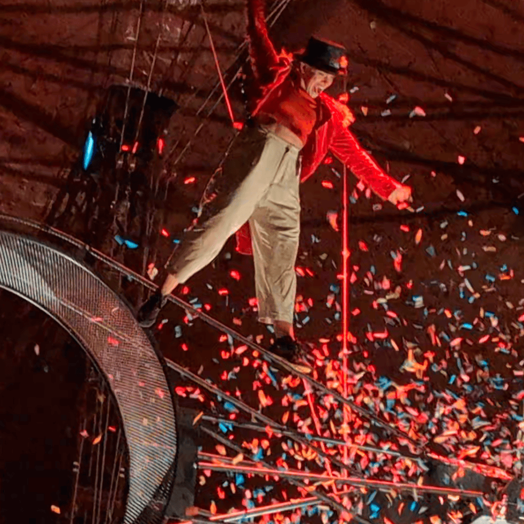 Image of a circus performer in the air surrounded by confetti