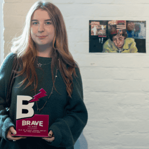 Elsie Calder holding the Young Artist of the Year award in front of her artwork