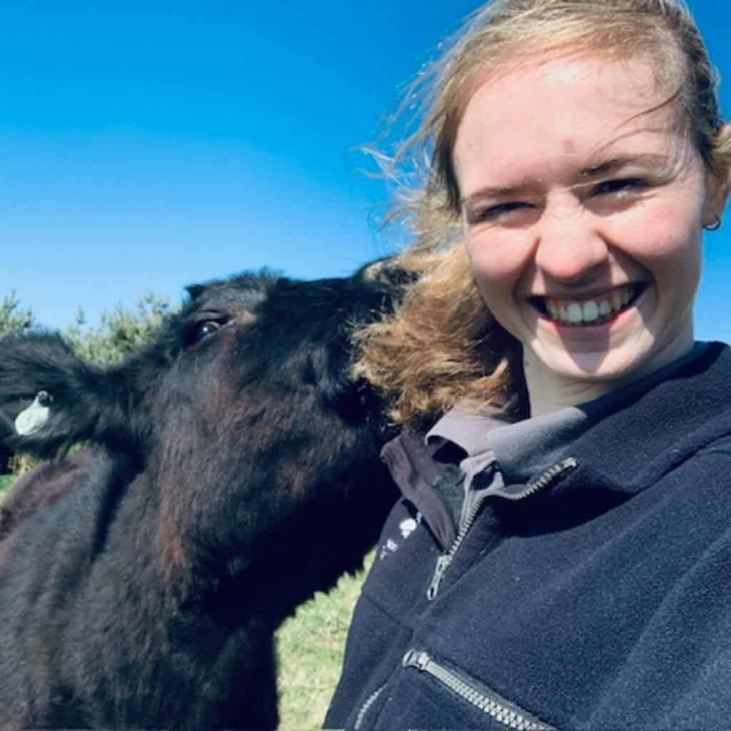 A National Trust Ranger smiles with a cow