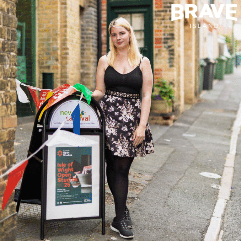 A young artist poses with the Isle of Wight Open Studios sign on the street outside New Carnival