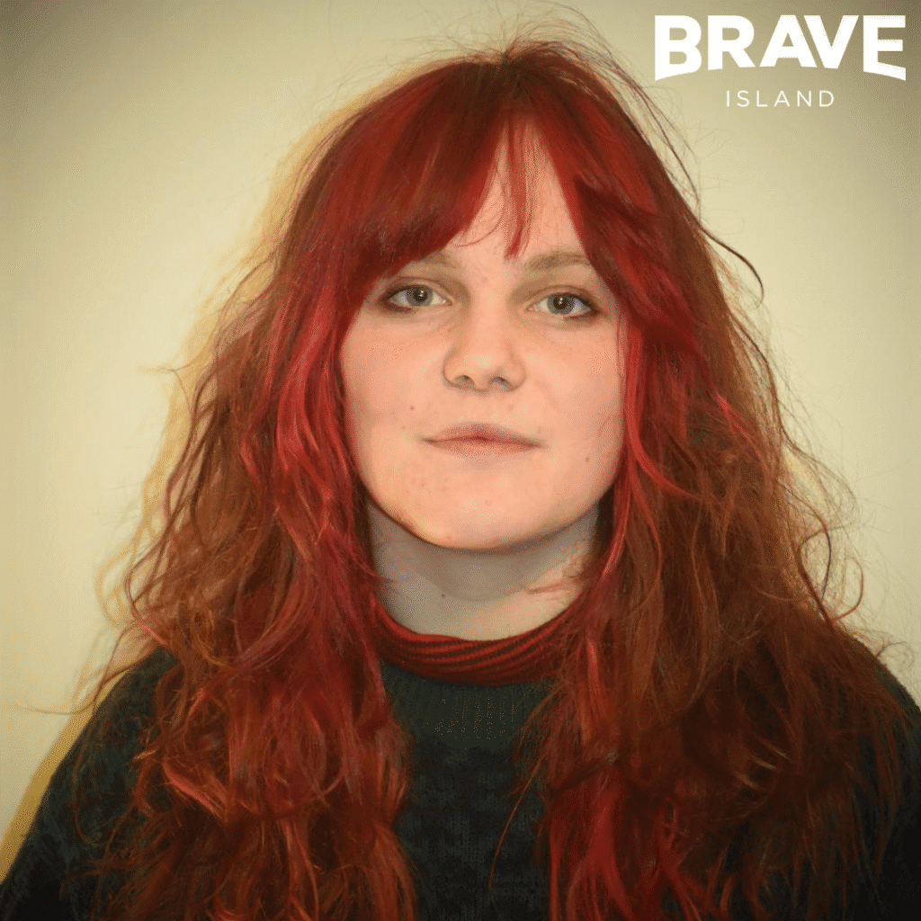 A "headshot" photograph of Young Creative of the month for February, Emma Wyeth. Emma has long red hair
