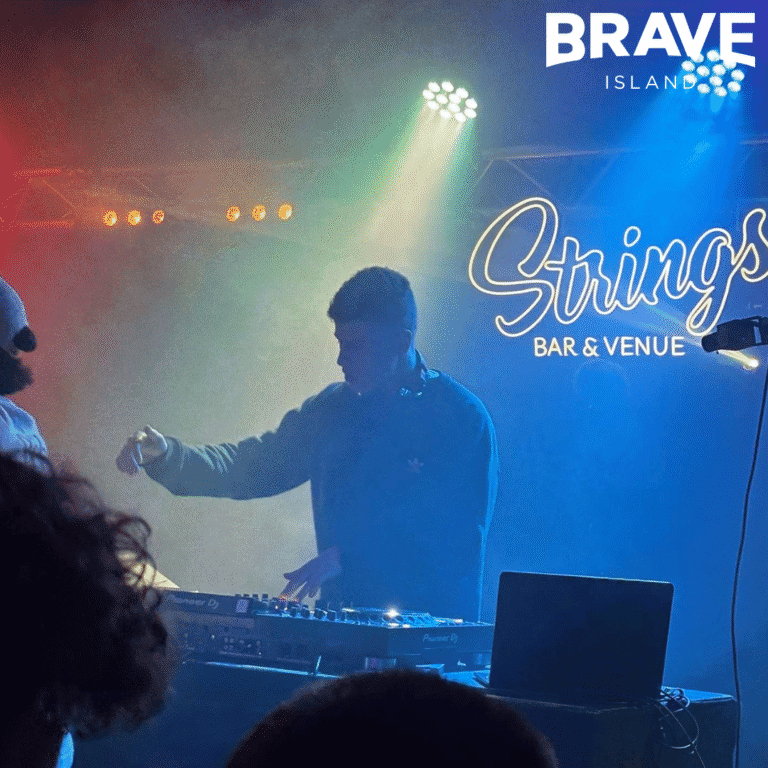 Sonnie, a young man, DJs behind the decks on stage at Strings Bar & Venue