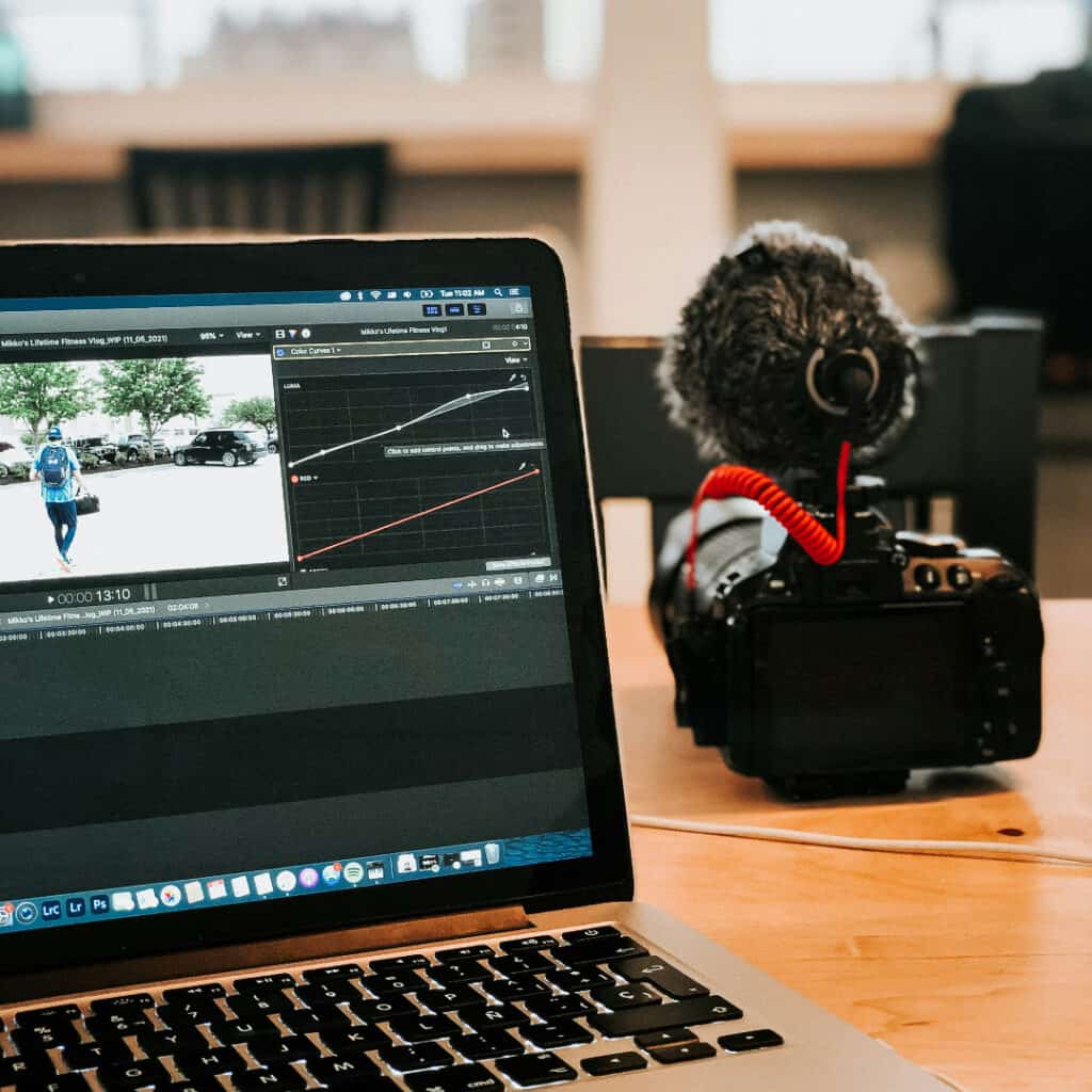 a camera and a laptop with video editing software open sit on a table